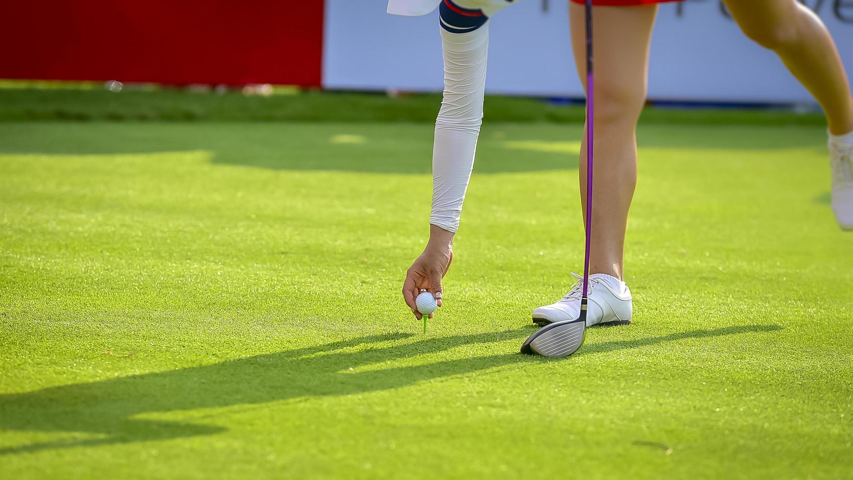 Golfer pushing white golf ball to hole at golf course in golf competition game , sunlight rays and blur background photo