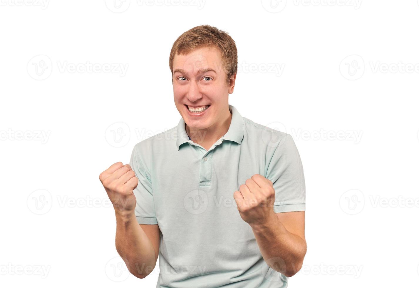 Successful smiling guy in mint T-shirt rejoices success, white background, triumph achievement photo