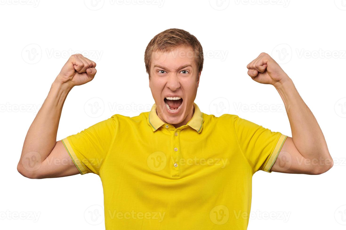 hombre joven divertido en camiseta amarilla casual levantando las manos y regocijándose del éxito, fondo aislado foto