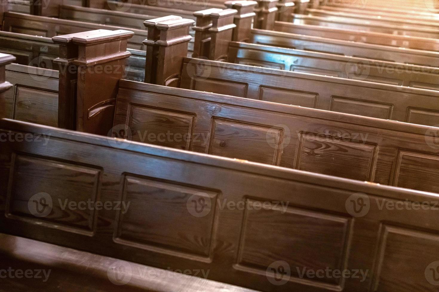 Cathedral benches. Rows of pews in christian church. Heavy solid uncomfortable wooden seats. photo
