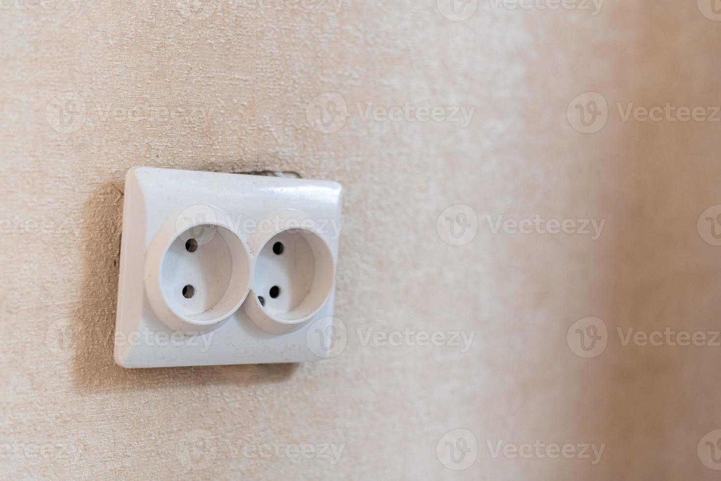 AC power double socket on wall, bad incorrectly installed, copy space. Socket for europlug type. Violations of safety standards. Fire-hazard. photo