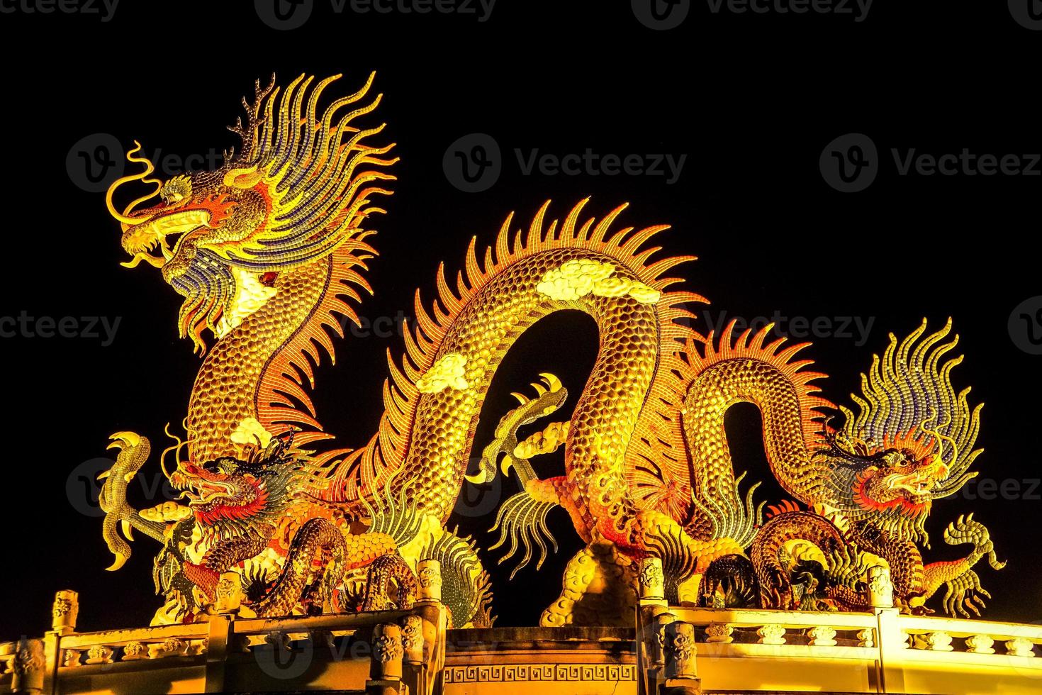 The Chinese style Golden statue of a magnificent golden king dragon with light up illuminated at night. photo