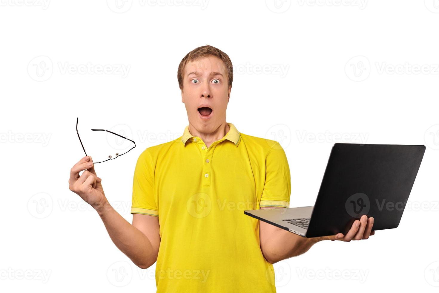 Surprised young man with laptop and glasses in hands isolated on white background photo