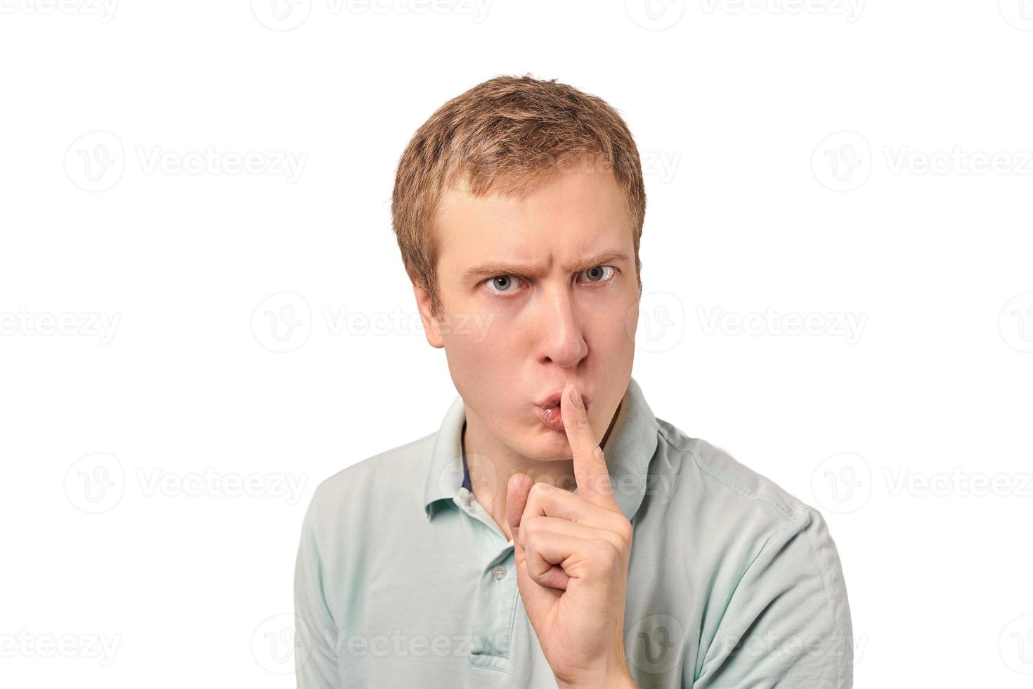 Funny guy in light gray Polo T-shirt asking to be quiet, silence gesture, white background photo