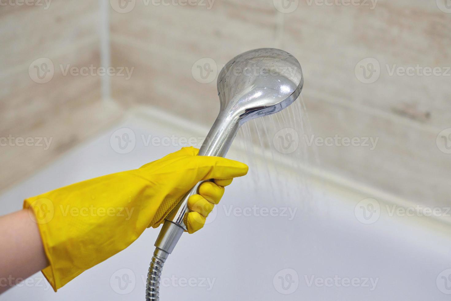 mano femenina sostiene el cabezal de la ducha con agua vertida, espacio de copia foto