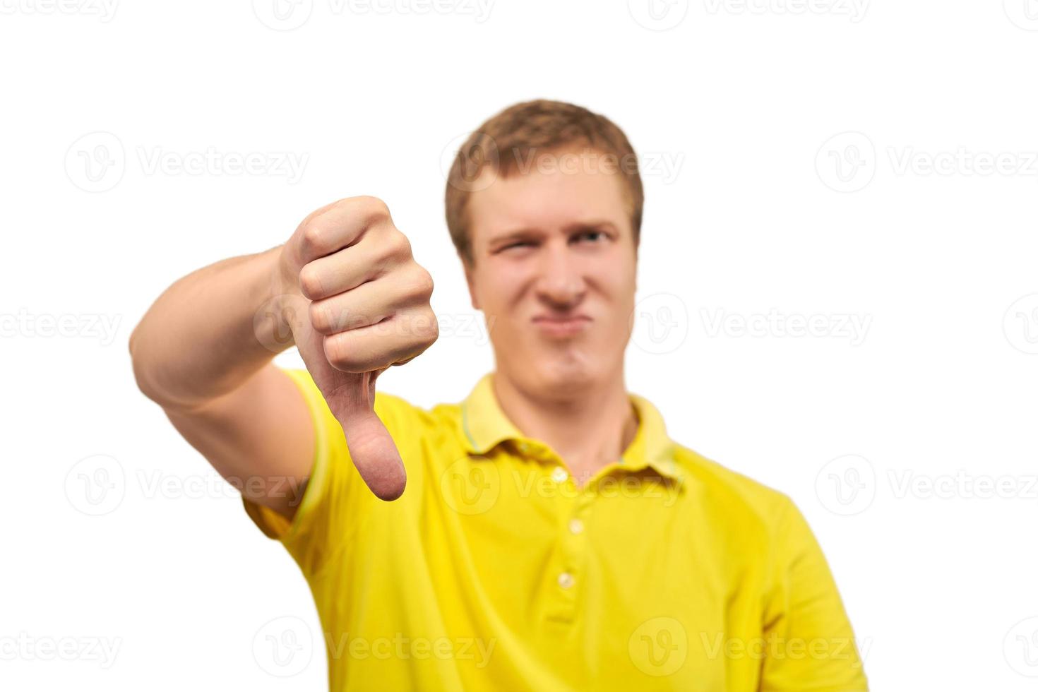 Unhappy annoyed man in yellow T-shirt showing thumbs down gesture isolated on white background photo