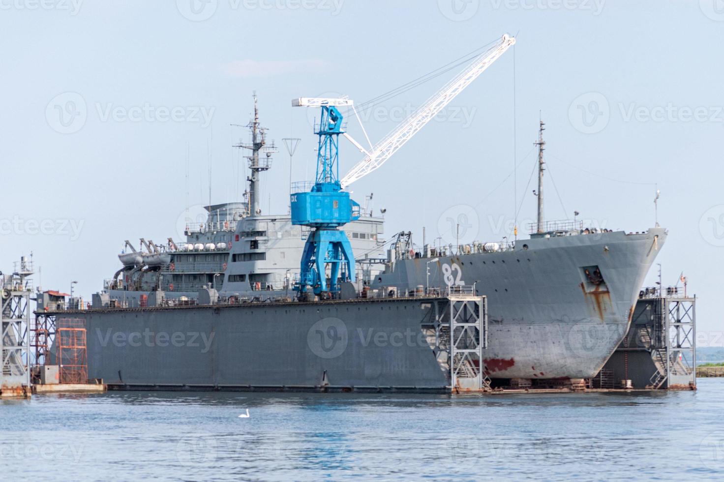 Large iron navy ships in shipyard for repair. Big crane in dockyard. Blue sea harbor photo
