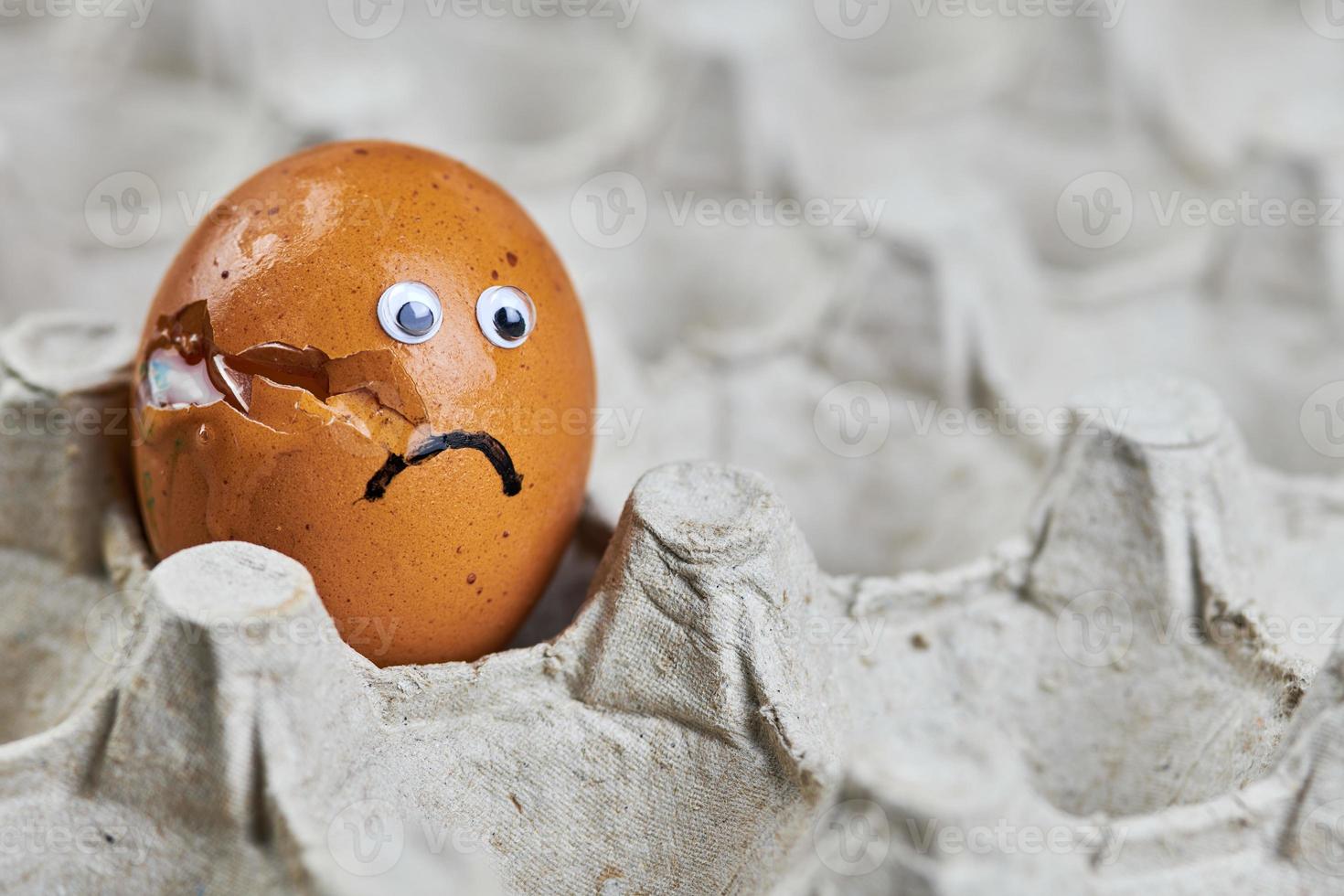 Sad cracked egg in paper egg tray photo