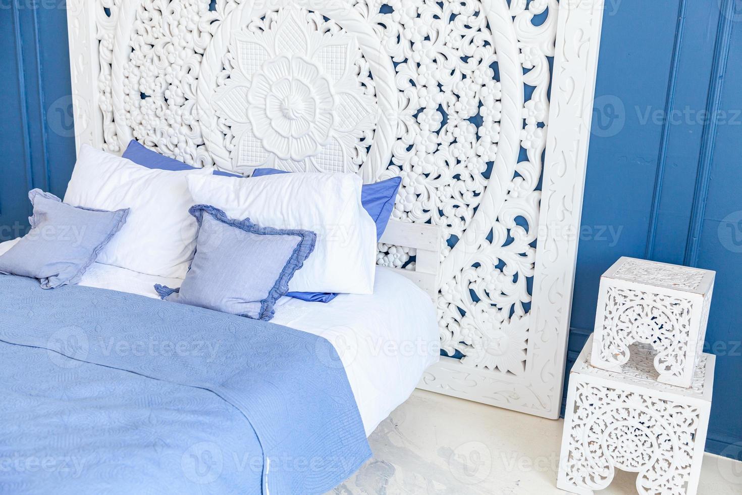 hermoso dormitorio interior clásico de lujo en color blanco y azul profundo con cama king-size y elegantes muebles tallados. Luminoso dormitorio interior moderno y elegante y sala de estar de estilo minimalista. foto