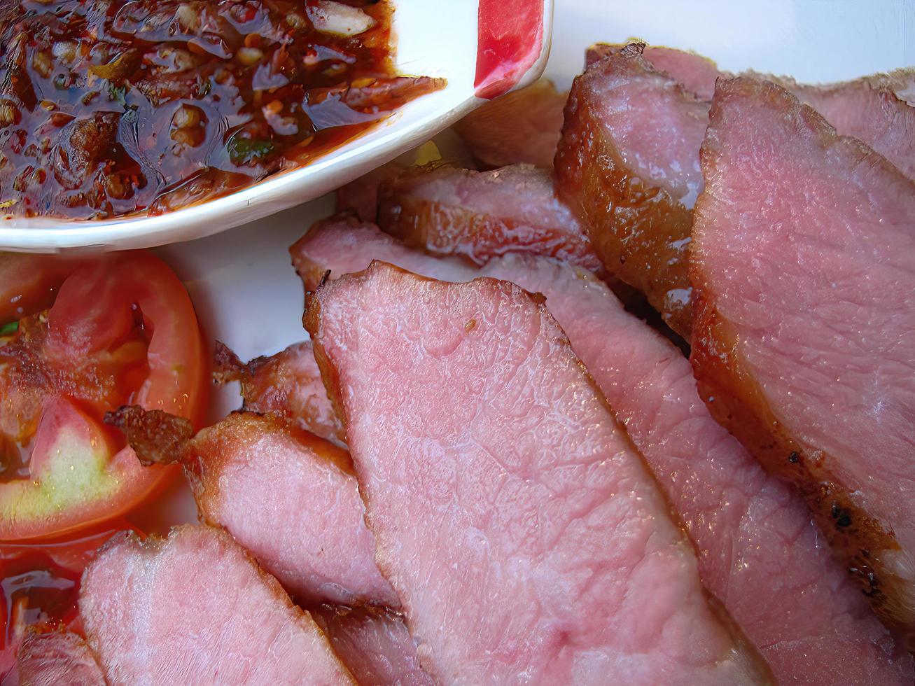 close-up full frame grilled pork neck sliced with Tamarind spicy sauce and fresh tomato photo