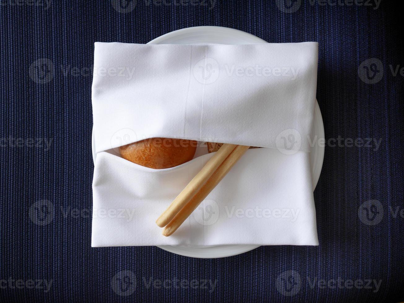 cclose-up warmed various kind of bread and bread sticks serving in the white napkin covered creative design with blue background photo