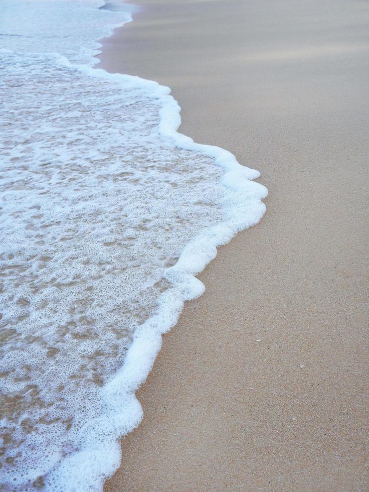 salpicadura de onda blanca en la playa de arena para papel tapiz de fondo foto