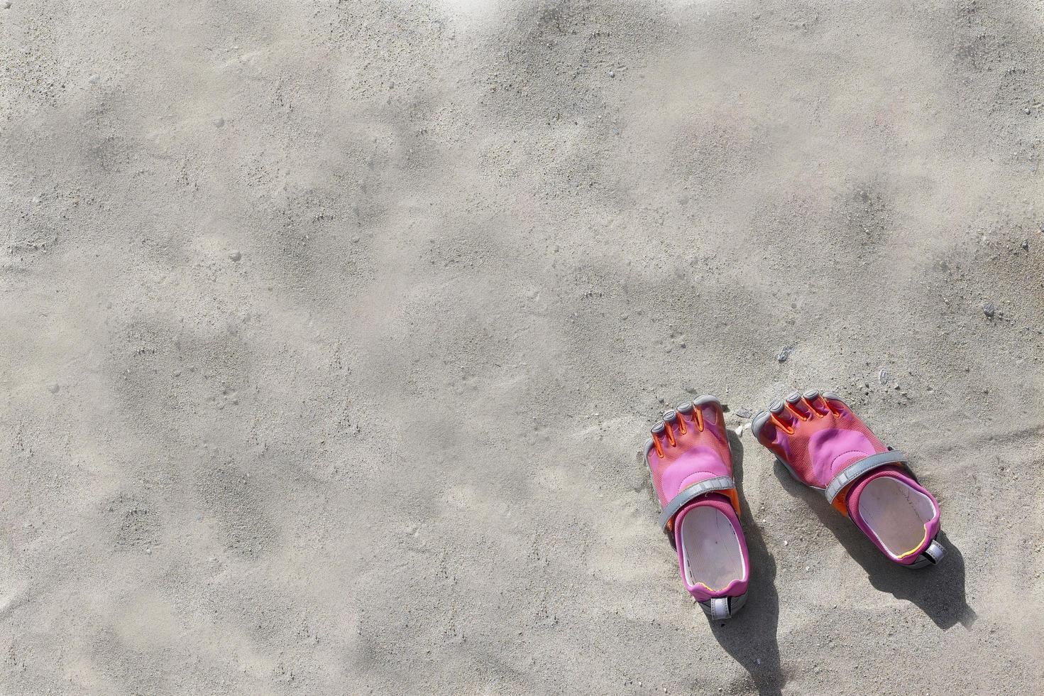 colorido calzado deportivo de agua gris rosa en la playa de arena para el fondo foto