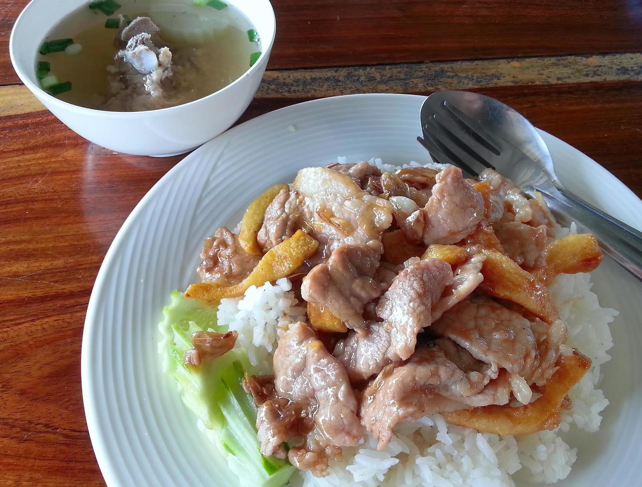 close-up stir fried garlic with slice pork top over rice with cucumber and soup Thai local food photo