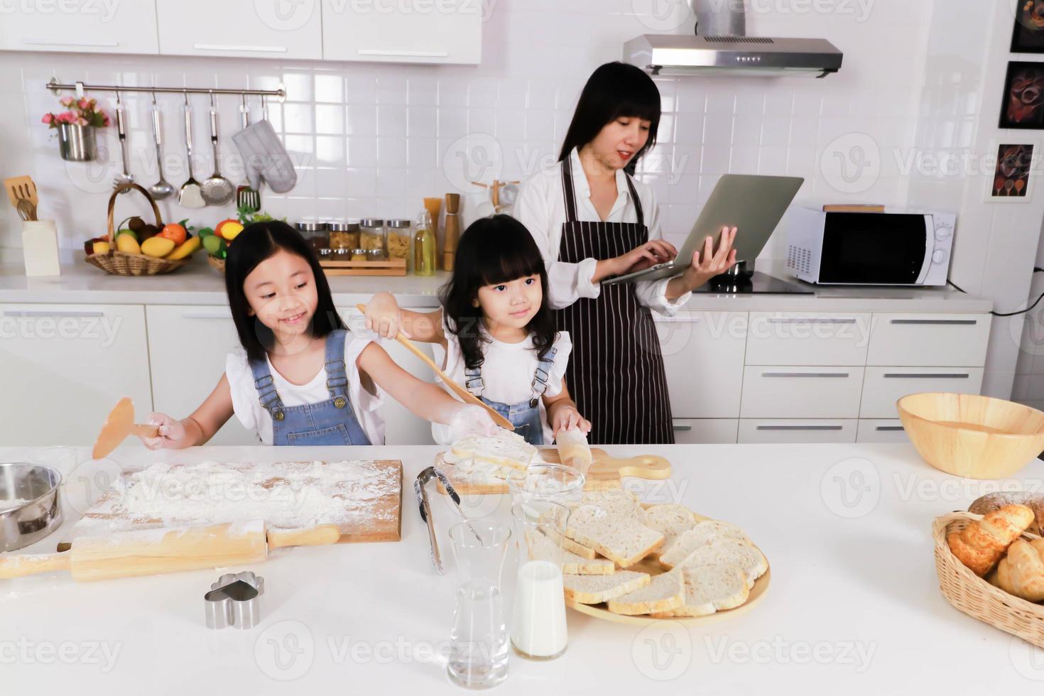 primer plano dos hijas hacen un horneado y la madre mira el cuaderno foto