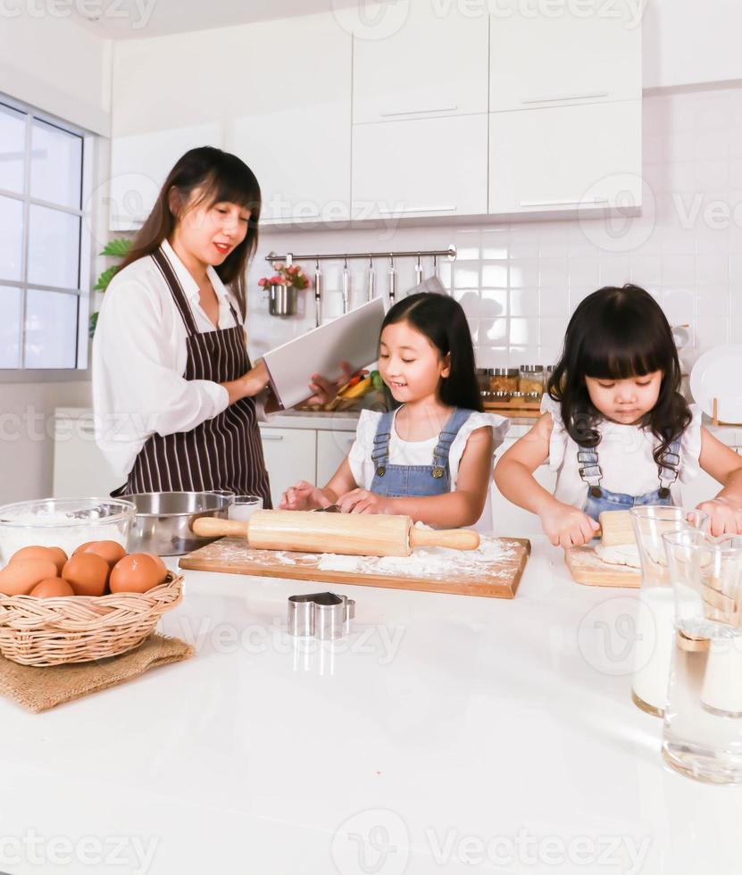 primer plano mamá leyendo un libro y el niño se divierte cocinando hornear en la cocina foto