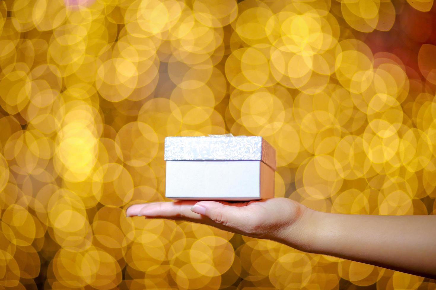 Merry Christmas and Happy New Year. Gift box in woman's hands with glowing bokeh. photo