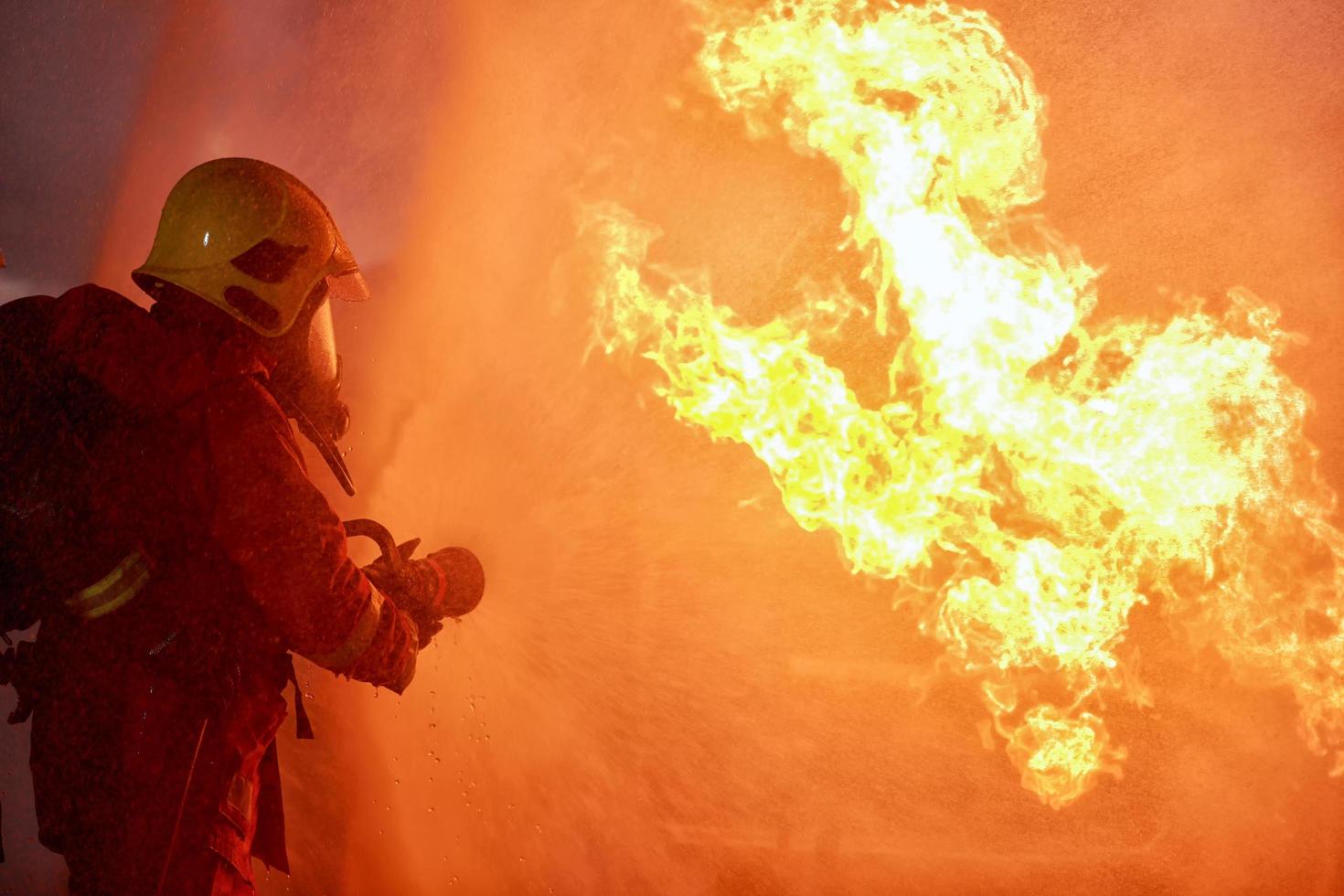 los bomberos combatiendo un incendio con una manguera y agua durante una extinción de incendios foto