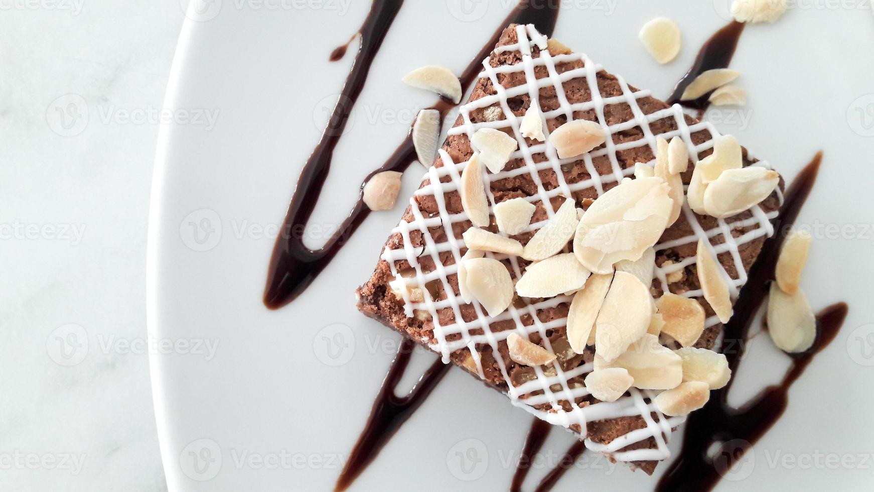 vista superior de brownie de chocolate con almendras en rodajas sobre fondo de plato blanco foto