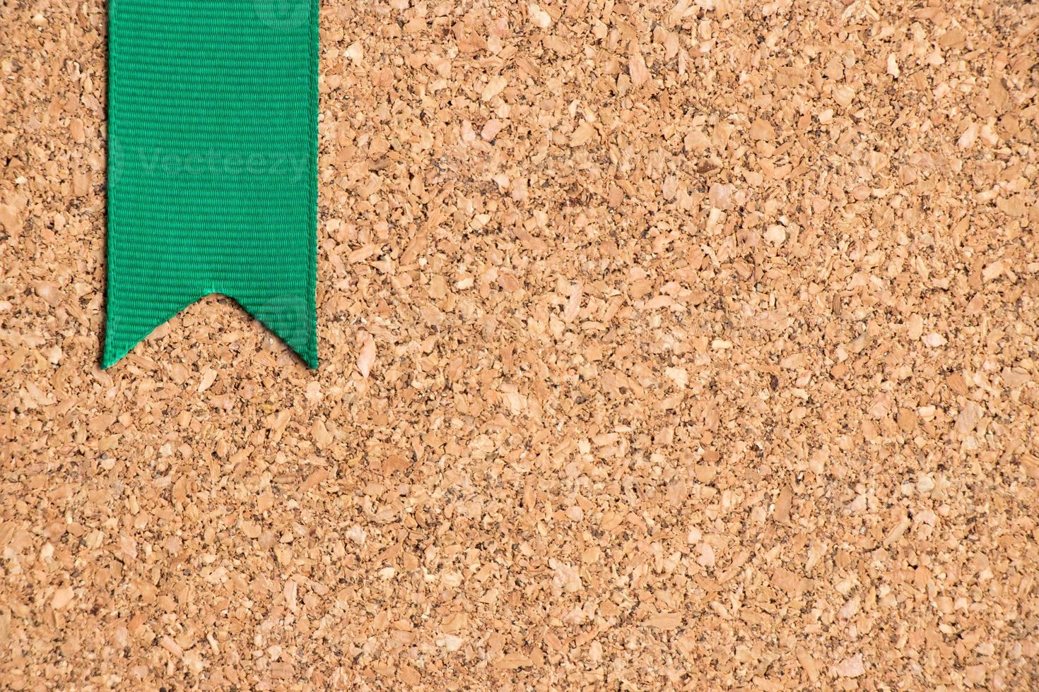 Green ribbon on cork board texture background photo