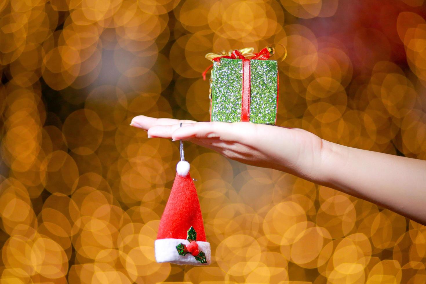 Merry Christmas and Happy New Year. Gift Christmas in woman's hands with glowing hearts bokeh. photo