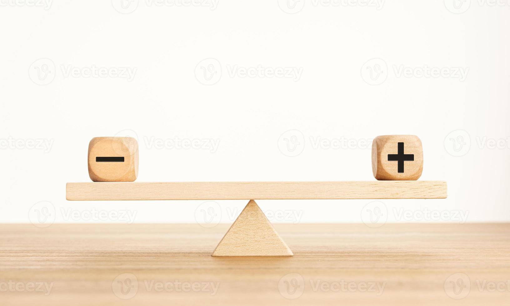 Plus and minus balance concept. Positive and negative symbols on wooden blocks are in balance on a wooden seesaw. Copy space photo
