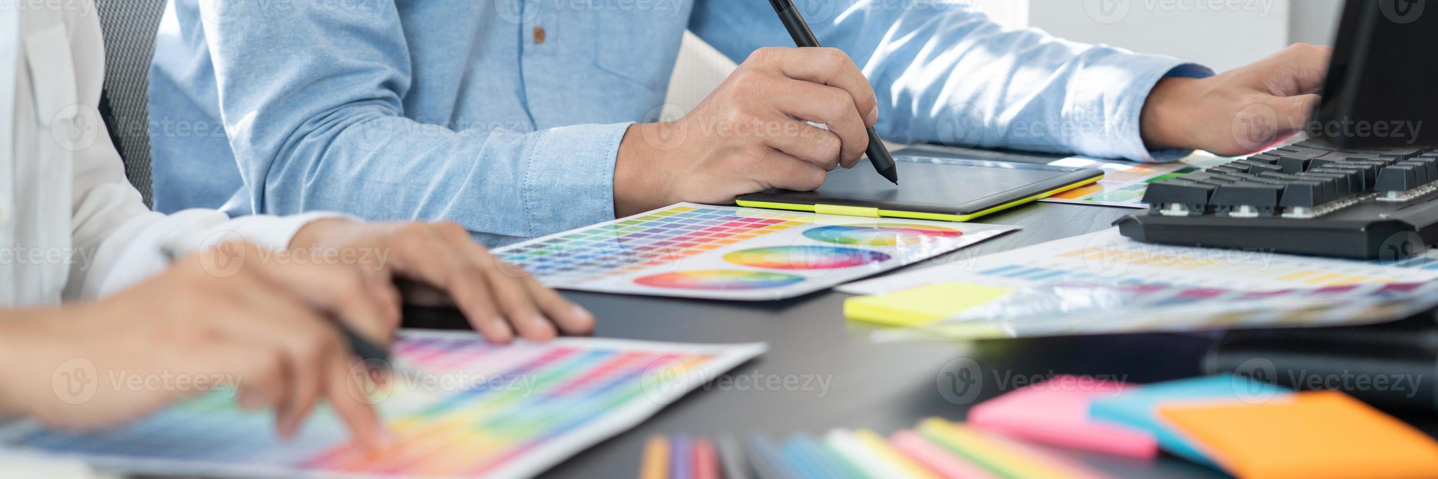 diseñador gráfico o creativo trabajando juntos coloreando usando una tableta gráfica y un lápiz en el escritorio con un colega. foto