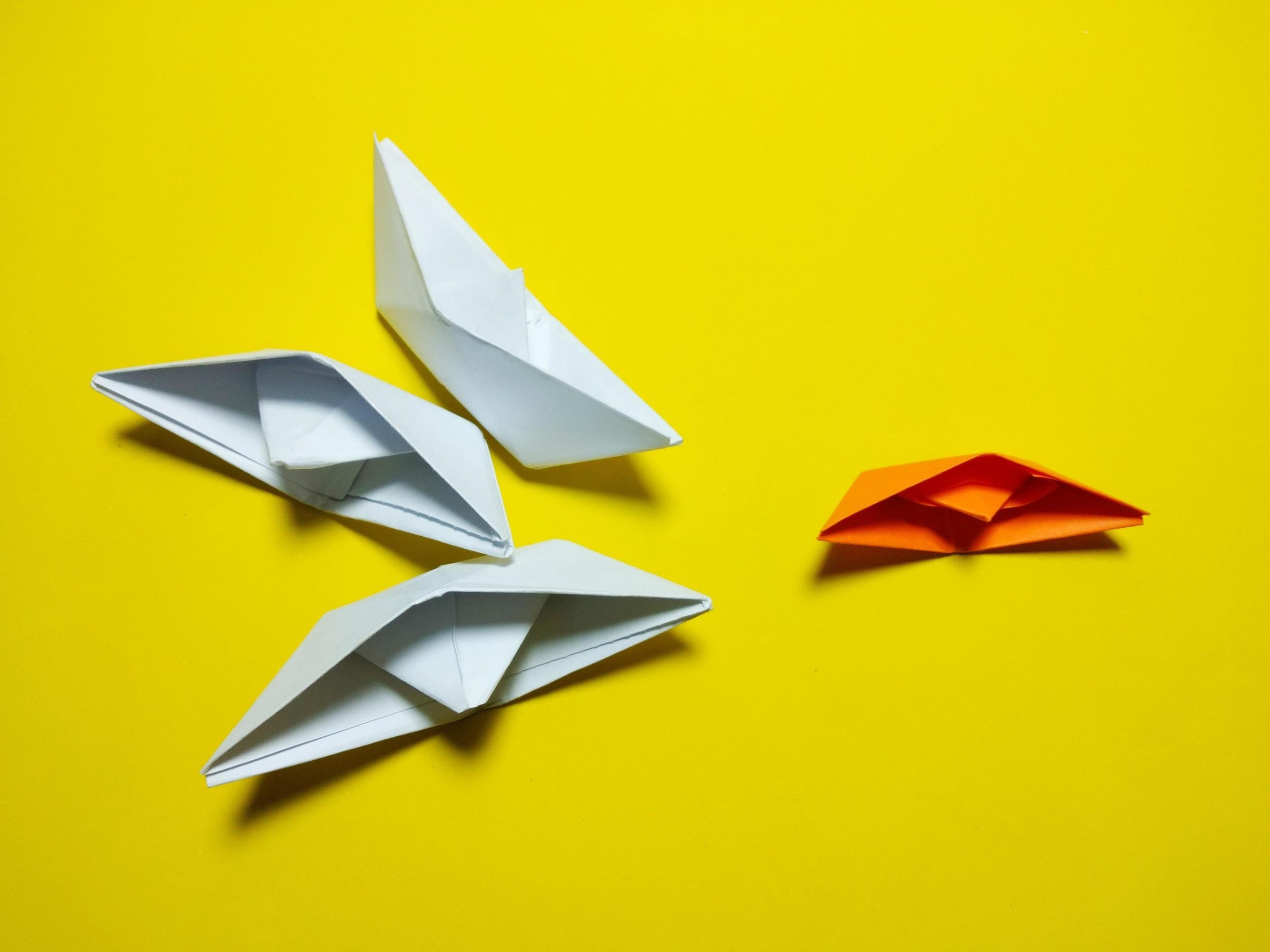 orange white paper boat falling Yellow background gives the concept of