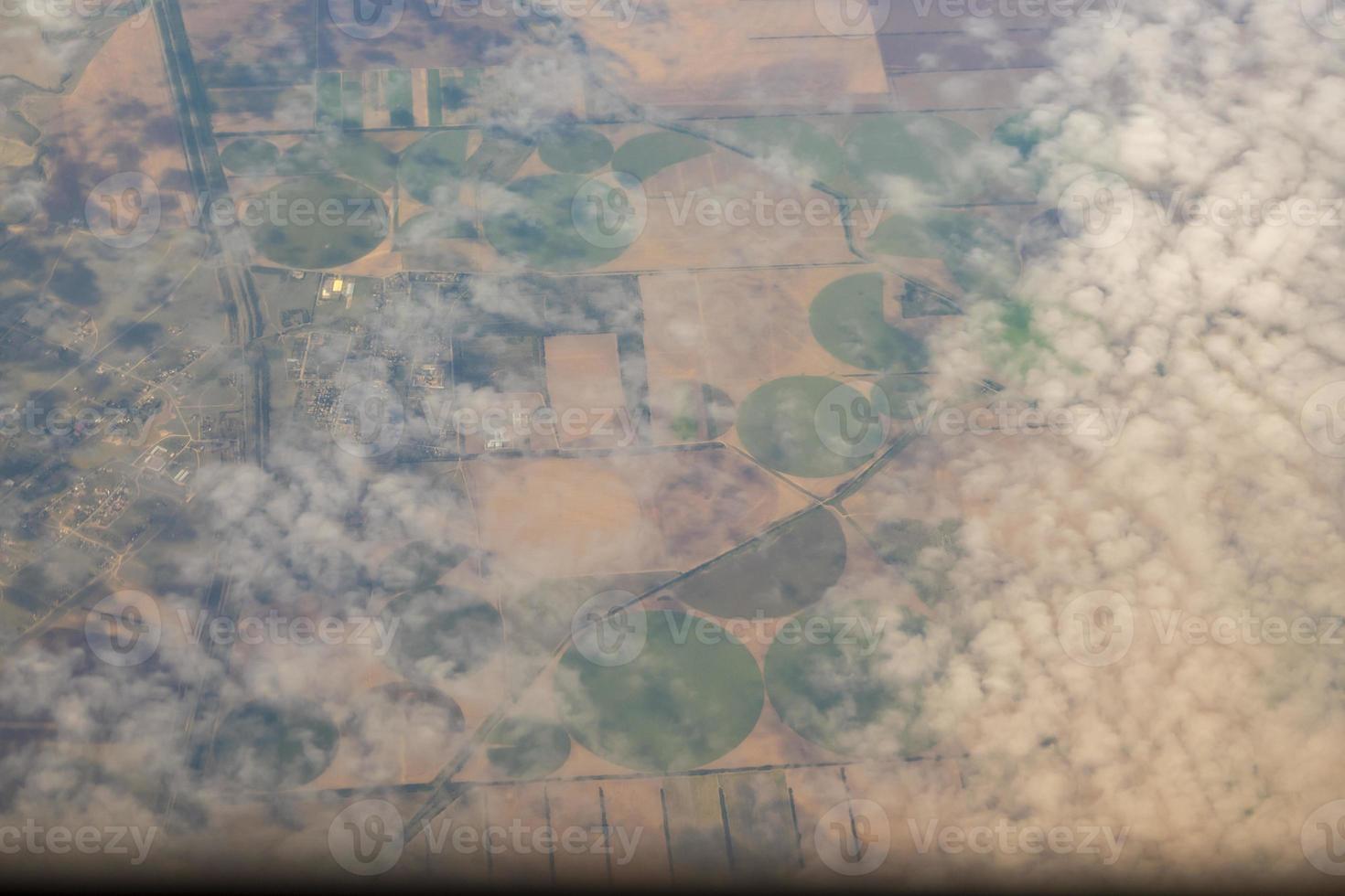 foto aérea de tierras de cultivo. vista desde el avión hasta el suelo. cuadrados de campos bajo las nubes