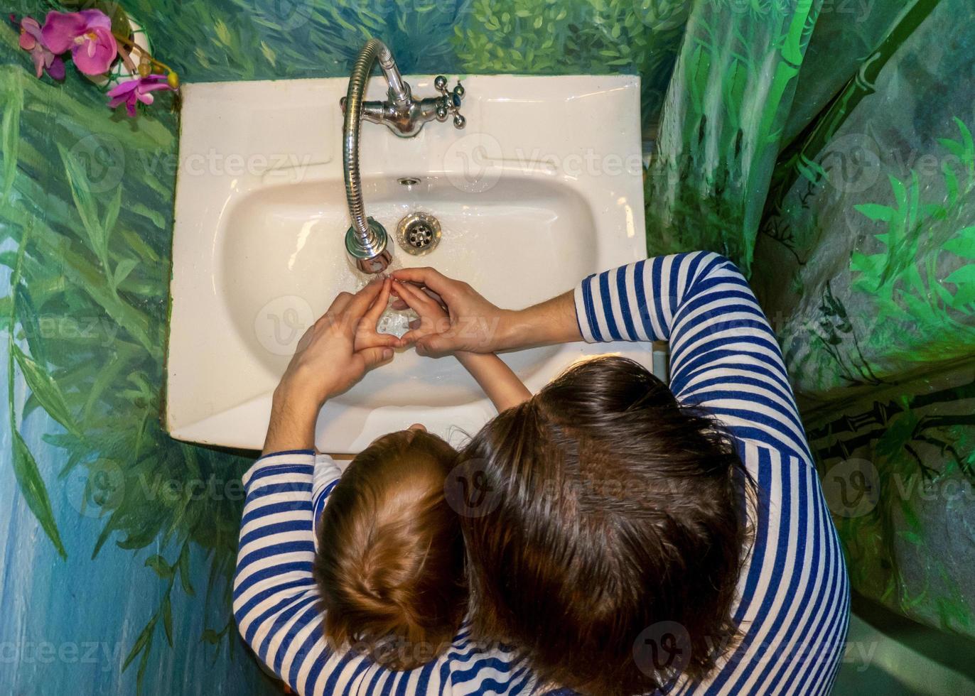 a man and a boy in vests wash their hands photo