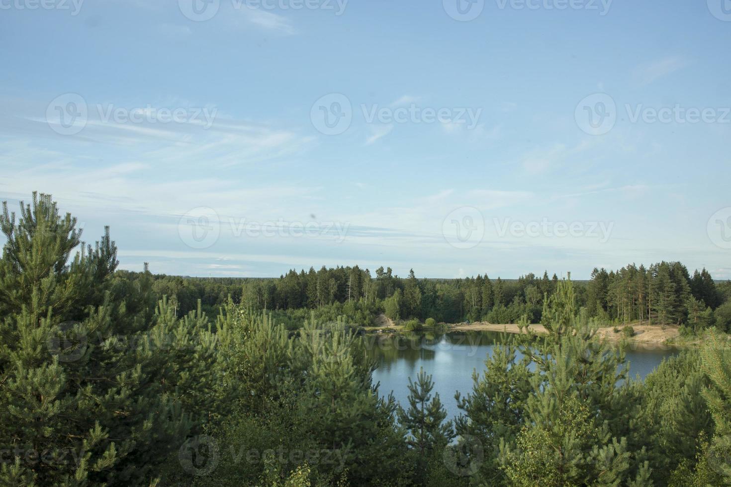 paisaje de verano con un hermoso lago con abetos y montañas boscosas contra un cielo nublado foto