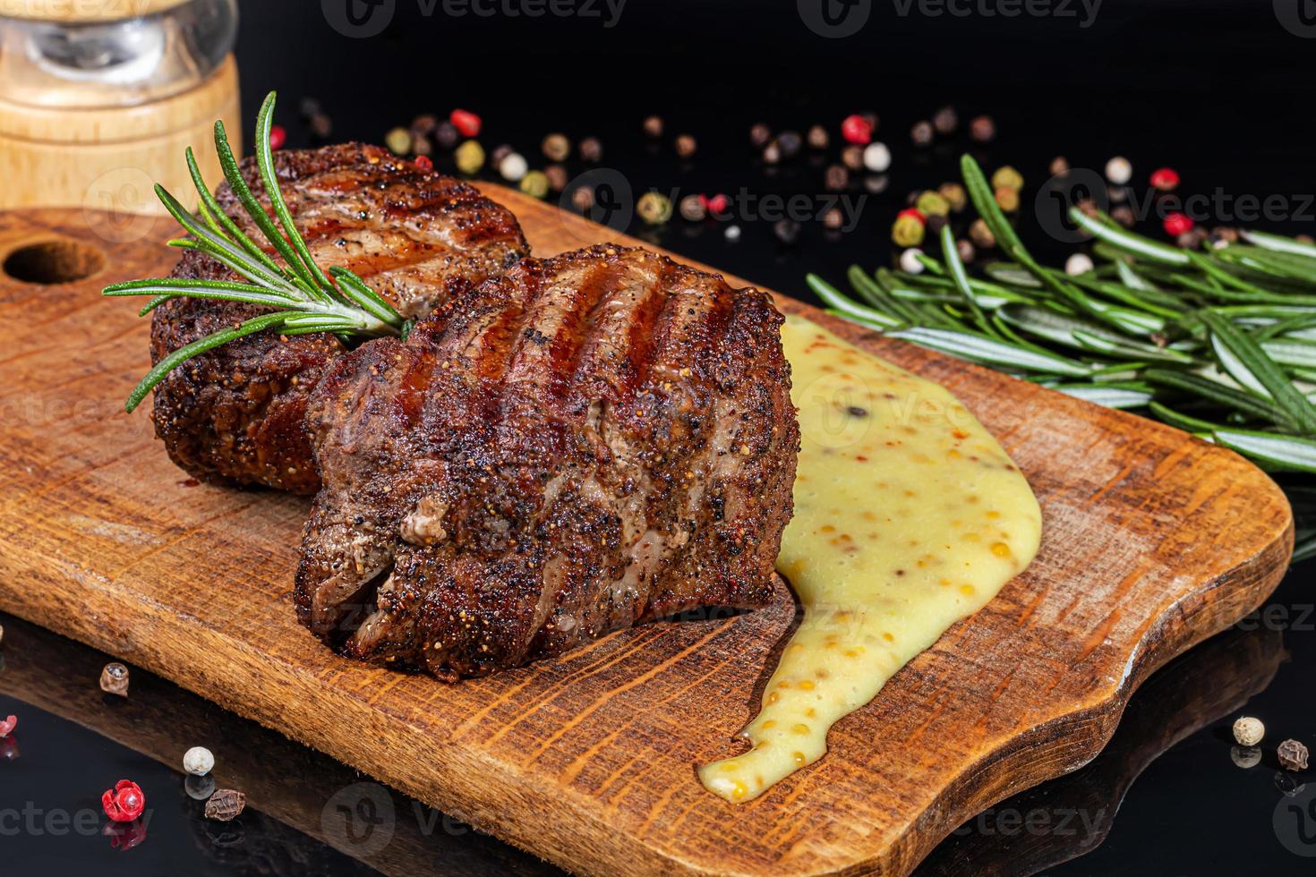 Meat dish on a plate with sauce. Chicken breast, fried pork. Parsley. Mustard sauces and ketchup. On a dark background. photo