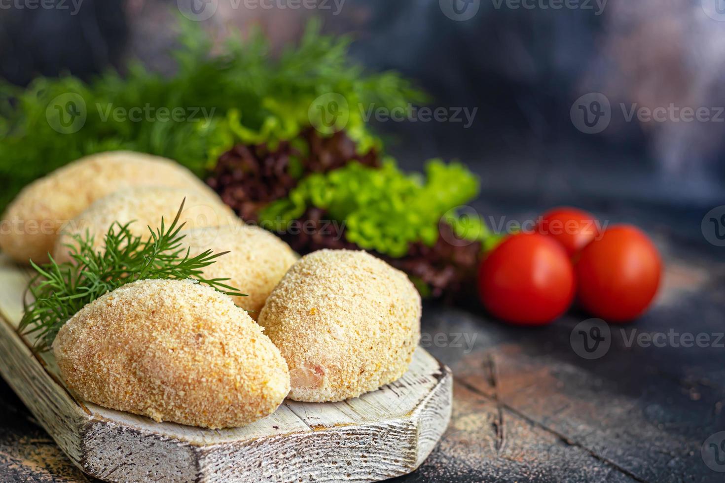 Semi-finished cutlets with breaded cheese or butter. Fast food preparation. On a dark background. photo