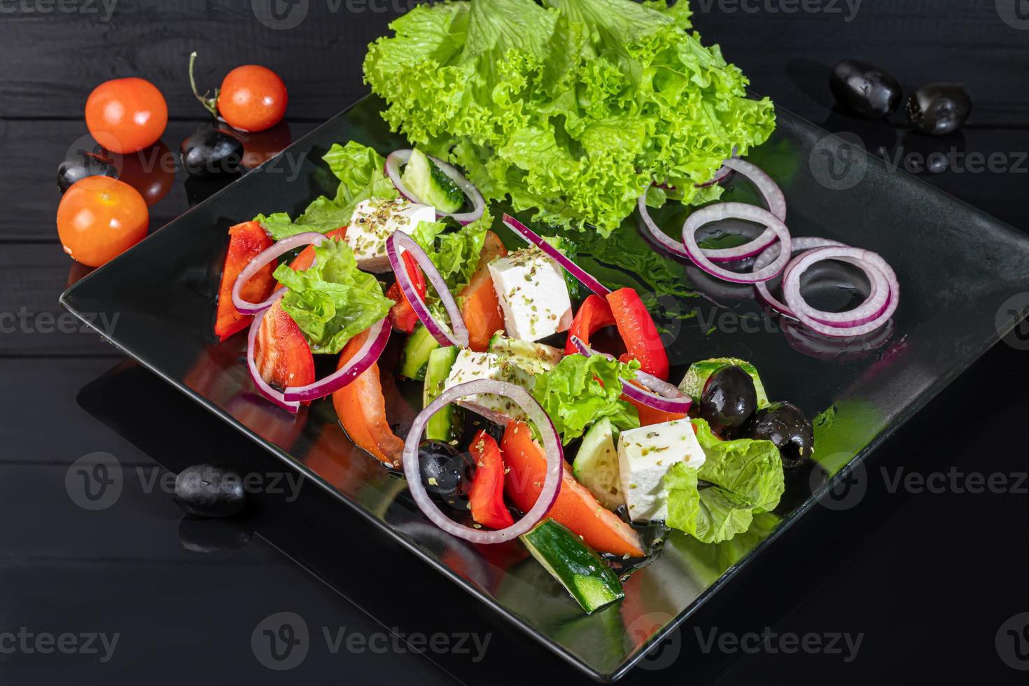 Greek salad with feta, tomatoes, olives and lettuce. On a dark background. photo