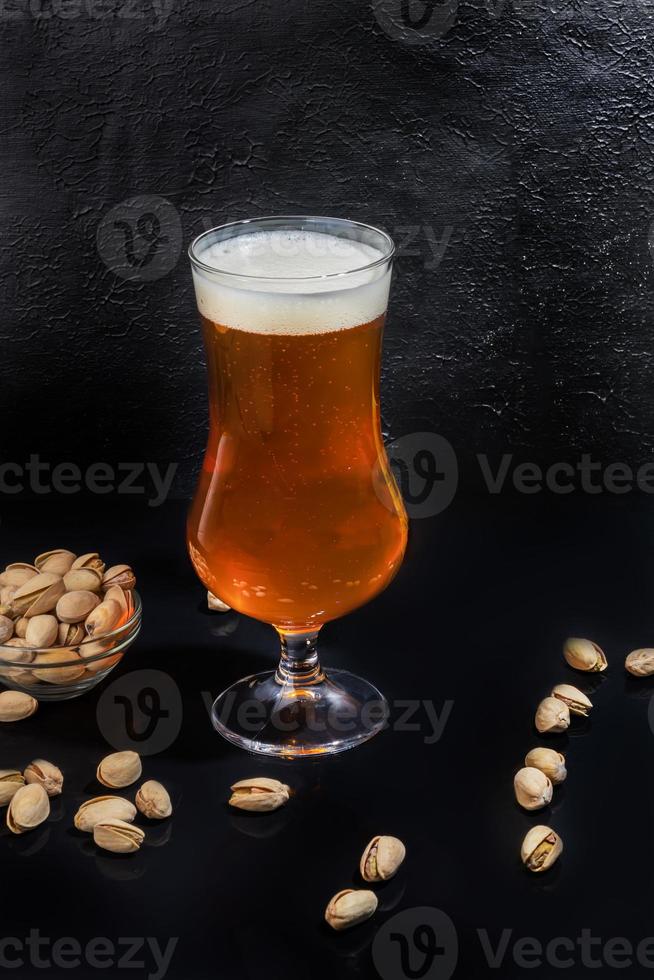 Glasses with different types of craft beer on a wooden bar. In glasses and bottles. Nuts and crackers on the table. On a dark background. photo