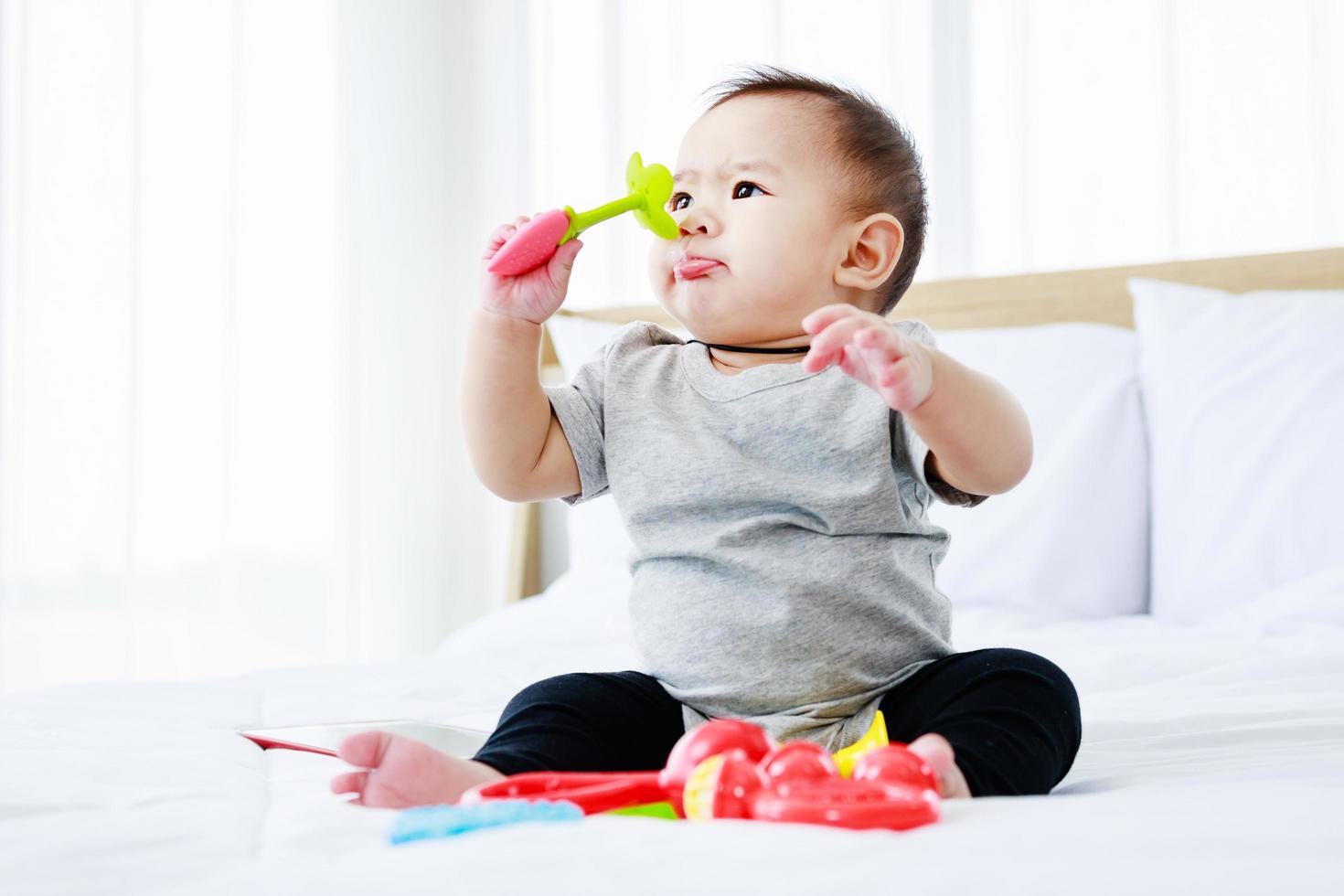 development in children. pretty baby play baby toy on bed. photo