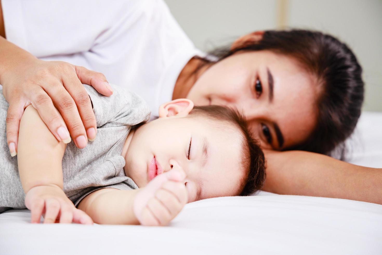 familia feliz, madre joven cuida a su bebé que duerme en la cama. foto