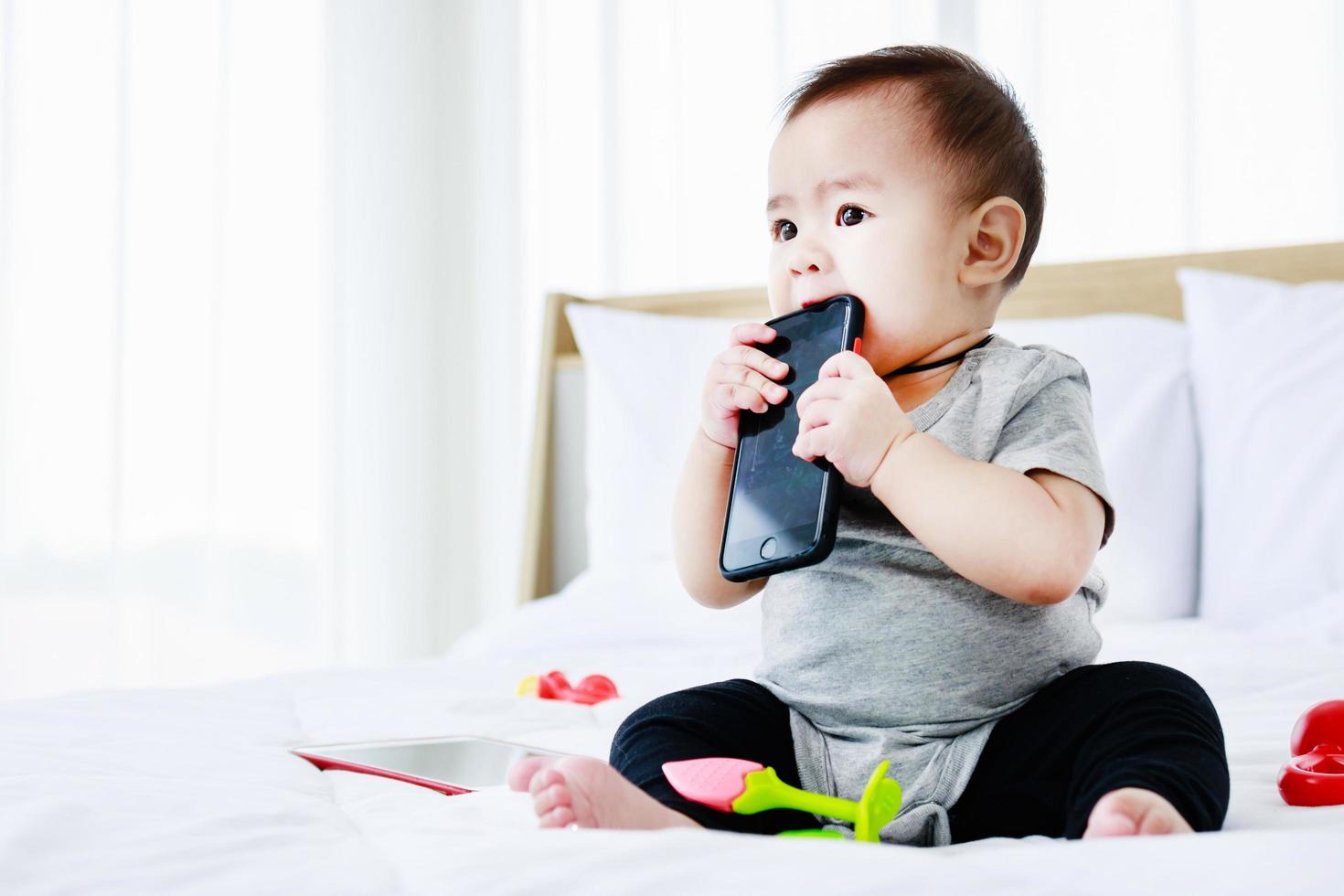 Cute baby girl playing with baby toys and smartphone. Smart funny child photo