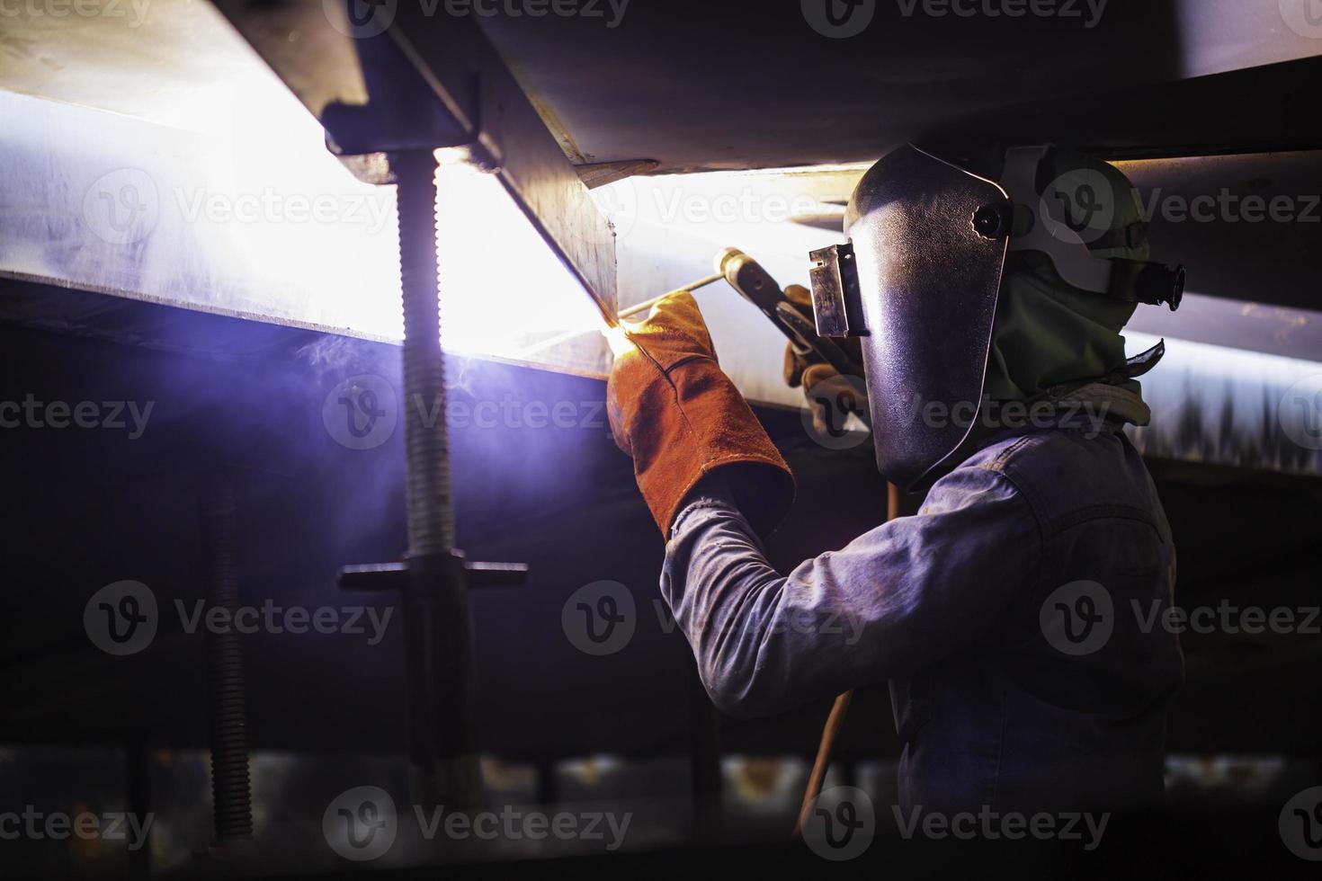 Male worker wearing protective clothing and repair welding industrial construction oil and gas or storage tank photo