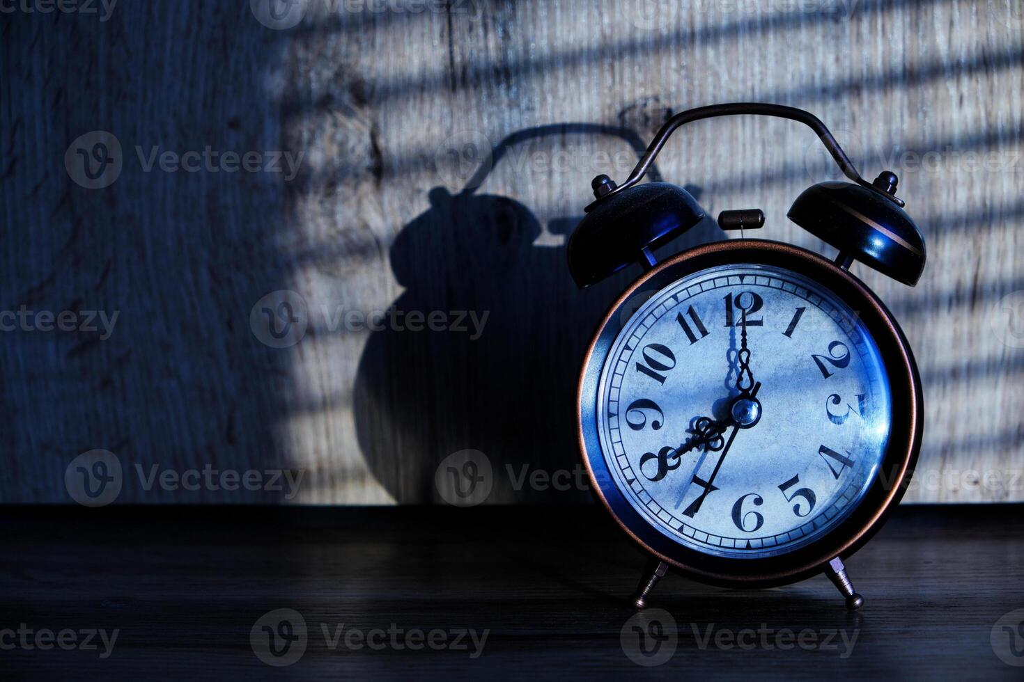 Old retro alarm clock early morning table, shadows from blinds in
