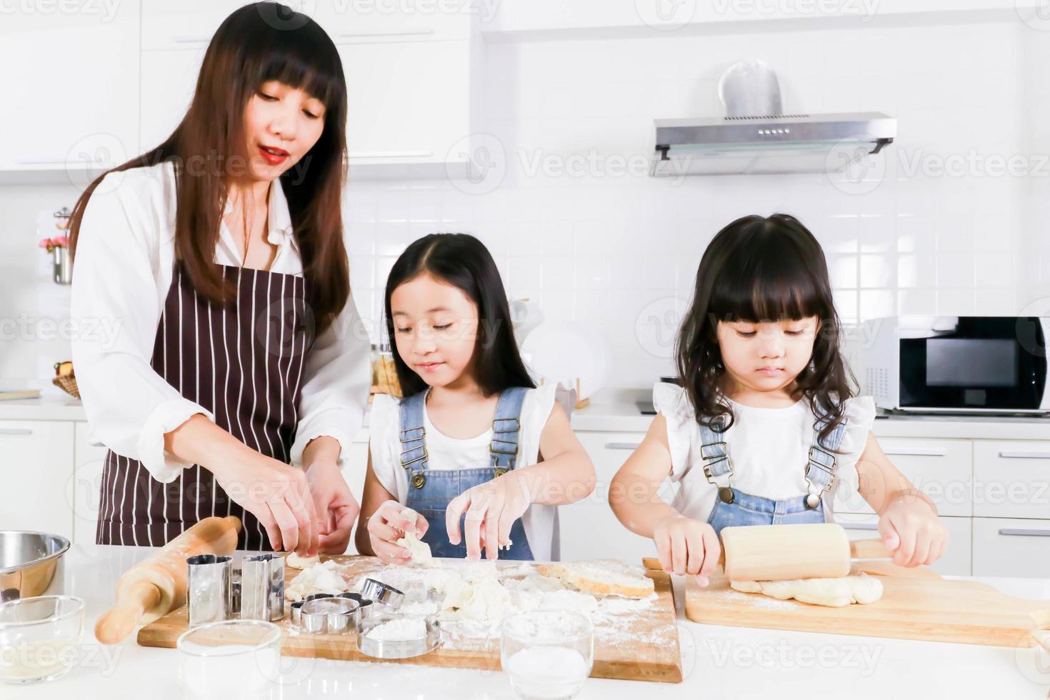 familia padre adulto mamá enseñando a dos niños pequeños hija haciendo panadería foto