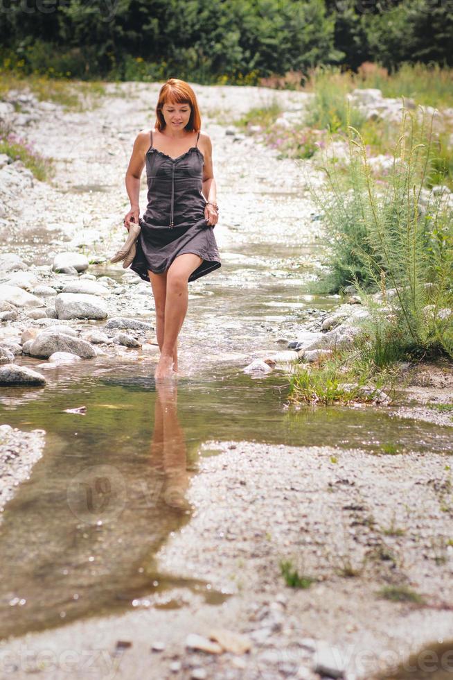 Woman walking by barefoot on river photo