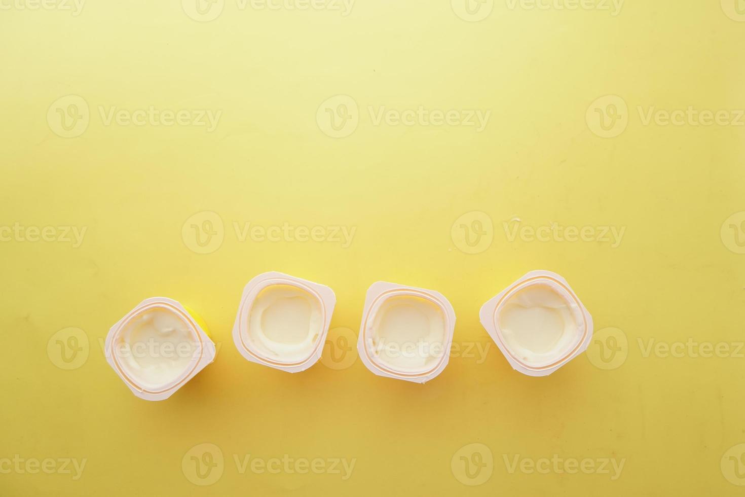 fresh yogurt in a plastic container and spoon on table photo
