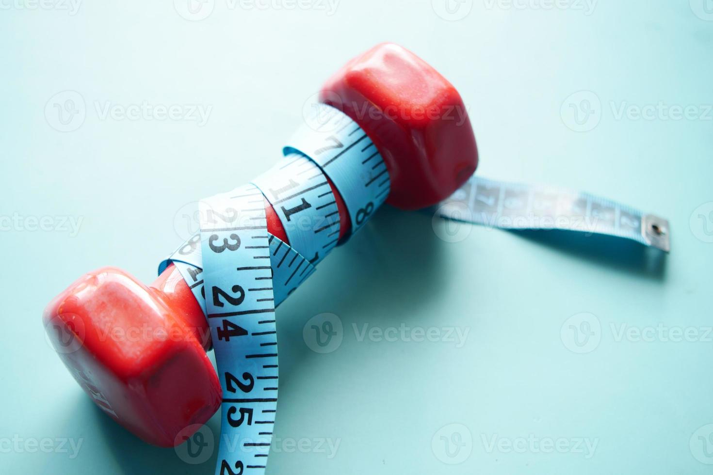 Fitness concept with dumbbell and measurement tape photo