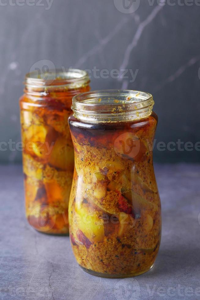 Homemade Mango Pickle in a glass jar on table , photo