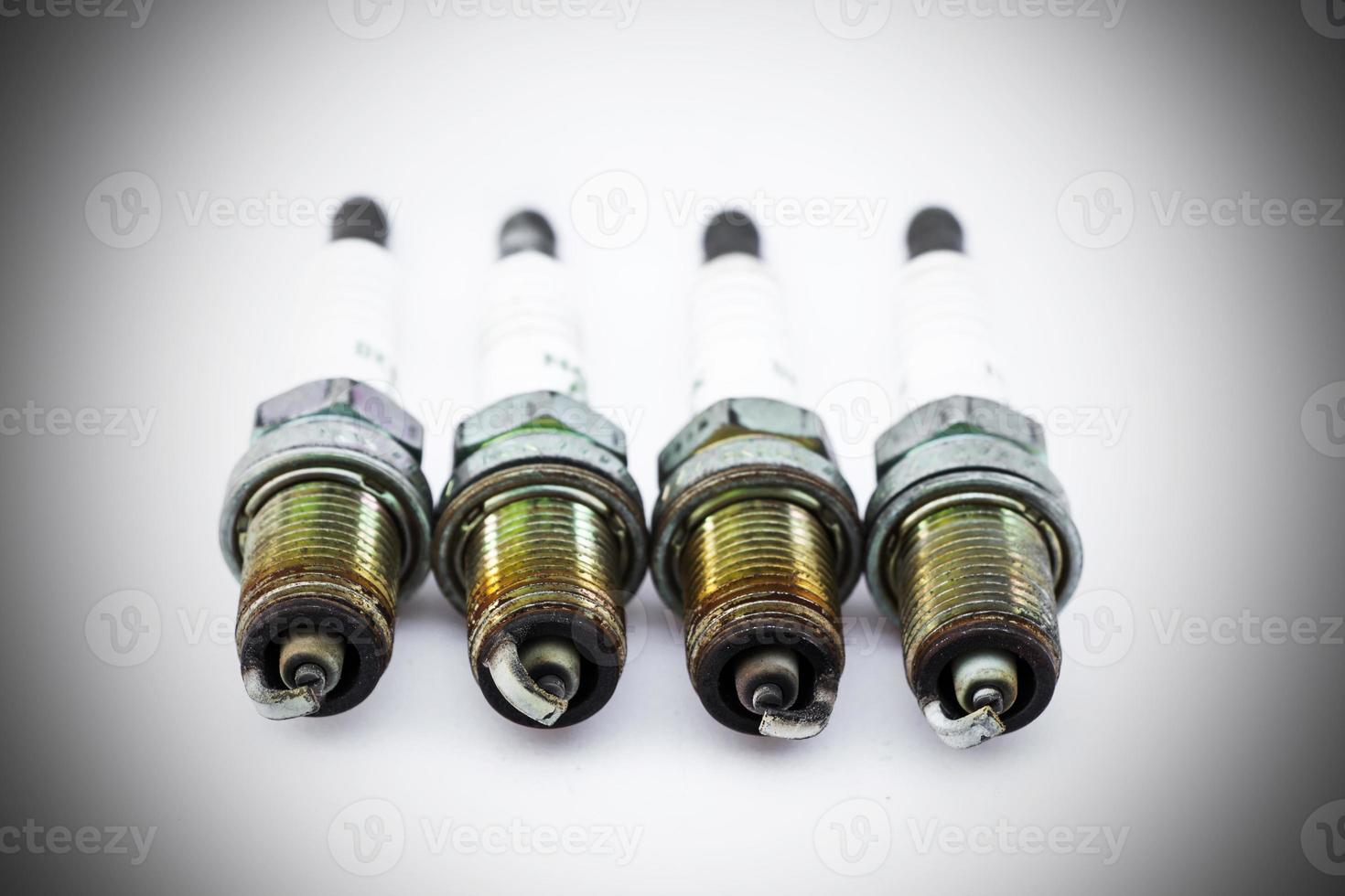 Four old burned spark plugs isolated on white background photo