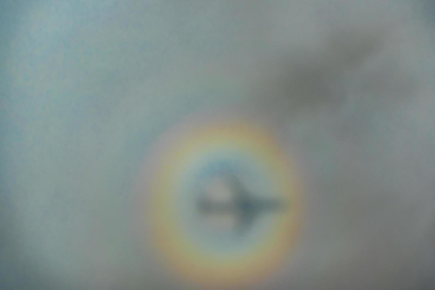 blurry shadow of the airplane on the cloud with the rainbow circle. traveling concept photo