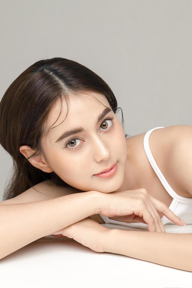 Beautiful young Asian woman model with perfect clean fresh skin on grey background. Face care, Facial treatment, Cosmetology, Plastic Surgery, Lovely girl portrait in studio. photo