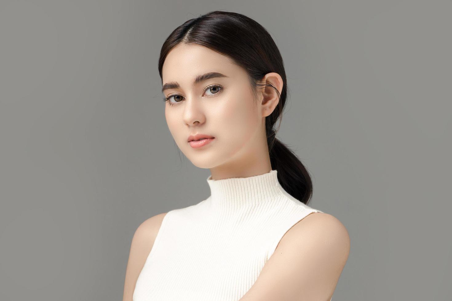 Beautiful young Asian woman model with perfect clean fresh skin on grey background. Face care, Facial treatment, Cosmetology, Plastic Surgery, Lovely girl portrait in studio. photo