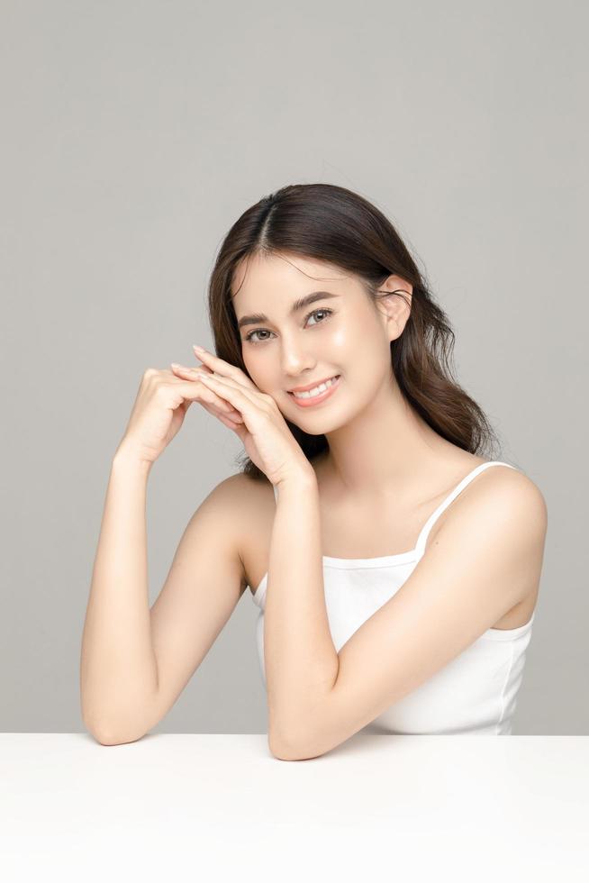 Beautiful young Asian woman model with perfect clean fresh skin on grey background. Face care, Facial treatment, Cosmetology, Plastic Surgery, Lovely girl portrait in studio. photo